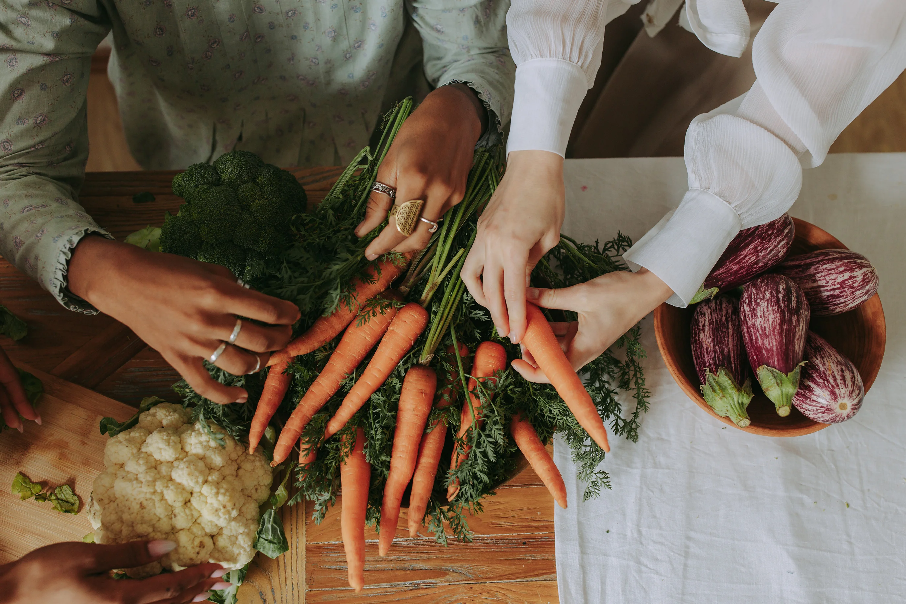 two people touching carrot and broccoli